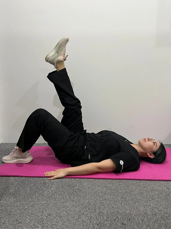 A woman doing a straight leg raise exercise