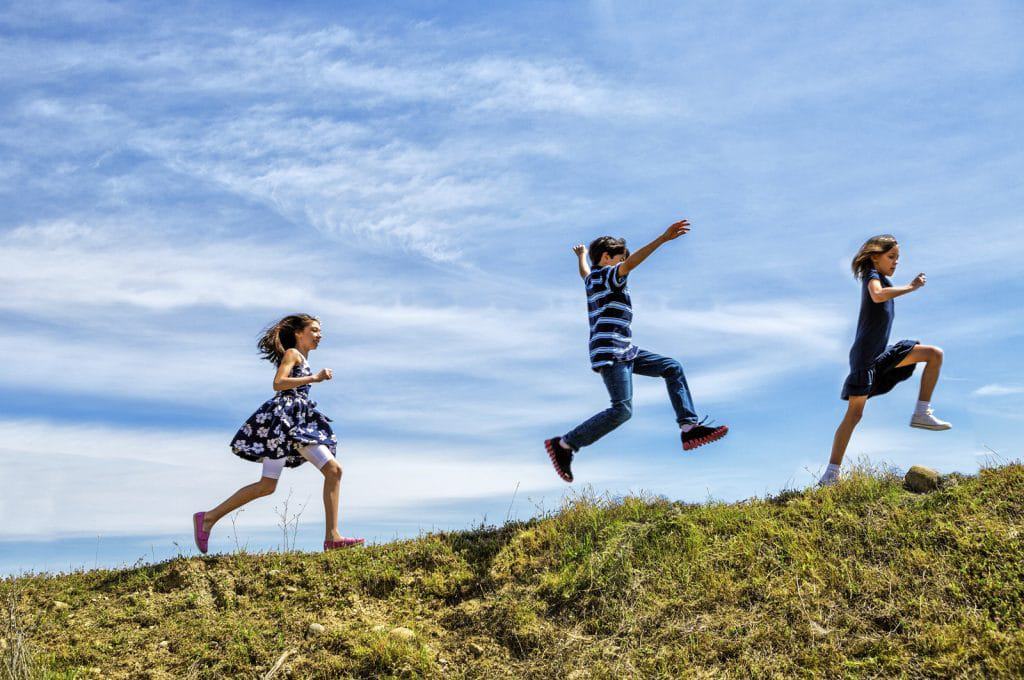 3 children jumping on a slope