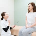 Asian female practitioner listening to female patient's symptom and explaining treatment method