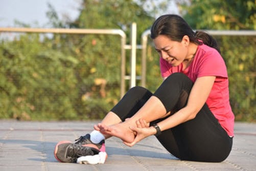 Woman with ankle pain, considering chiropractic treatment with dry needling in Singapore